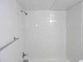 Dallas apartment for rent - A white tiled shower with a white tub and silver fixtures.