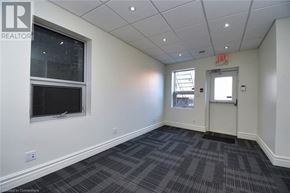 Hamilton apartment for rent - A room with a grey carpet and a white wall with a window and an exit sign.