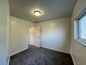 Glassport house for rent - A room with a carpeted floor and a window on the right side.