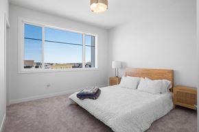 St. Albert apartment for rent - A bedroom with a large bed and a view of the outside through the window.