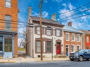 Frederick house for rent - A blue Ford truck is parked on the street in front of a two-story brick house.