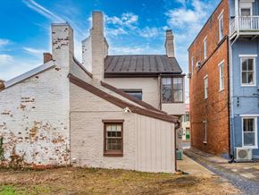 Frederick house for rent - A white house with a brown roof and a window is in front of a blue building.