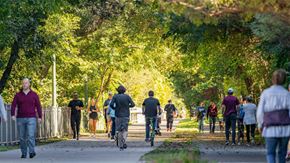 Dallas apartment for rent - A group of people walking and riding bikes on a path in a park.