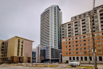 Hamilton apartment for rent - A tall building with many windows stands in front of a smaller building.