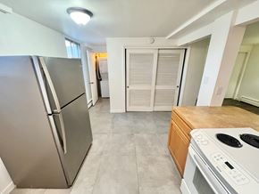 Arvada apartment for rent - A kitchen with a stainless steel refrigerator and a white stove top oven.
