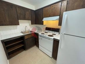 Longview apartment for rent - A kitchen with a white refrigerator, white stove, and brown cabinets.
