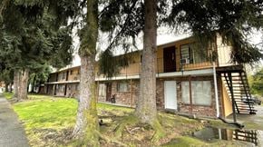 Longview apartment for rent - A building with a brown and beige exterior is surrounded by trees.