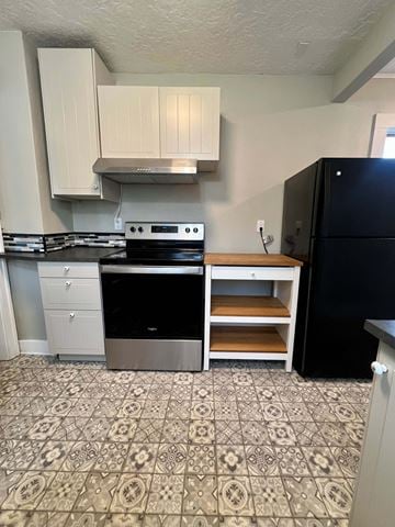 Longview house for rent - A kitchen with a black fridge and a stove top oven.