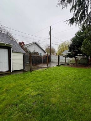 Longview house for rent - A grassy yard with a fence and a house in the background.