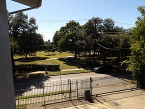 Dallas apartment for rent - A black gate blocks the road to a green park.