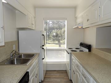 Dallas apartment for rent - A kitchen with white cabinets and a window with blinds.