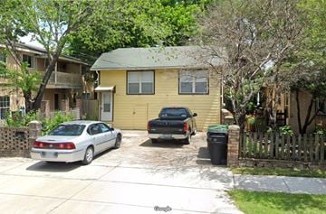Houston apartment for rent - A silver car is parked in front of a yellow house.
