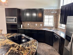 Houston apartment for rent - A kitchen with black cabinets and a granite countertop.