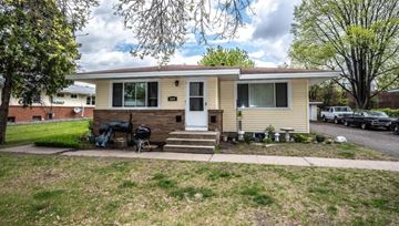 Fridley apartment for rent - A beige house with a black grill and a white door.
