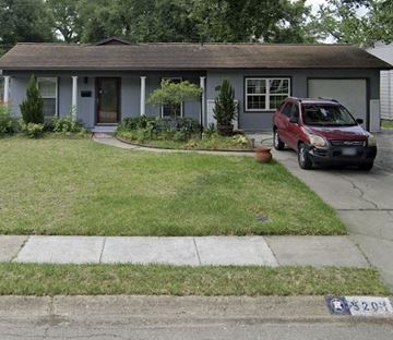 Houston apartment for rent - A red car is parked in front of a grey house.