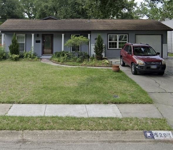 Houston apartment for rent - A red car is parked in front of a grey house.