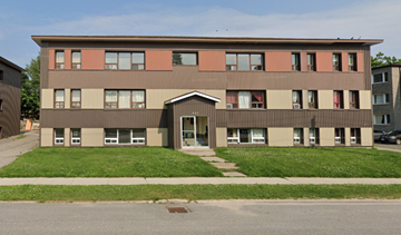North Bay apartment for rent - A building with a brown and beige facade has a green lawn in front.
