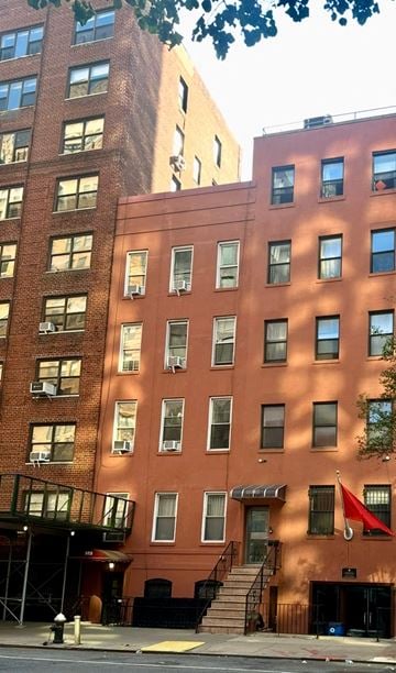 New York apartment for rent - A red building with a balcony and stairs leading to it.