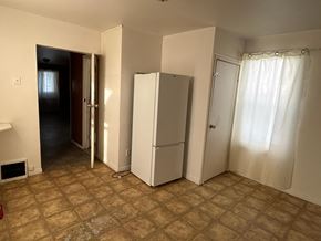 Prince Albert house for rent - A room with a white refrigerator, a white door, and a brown floor.
