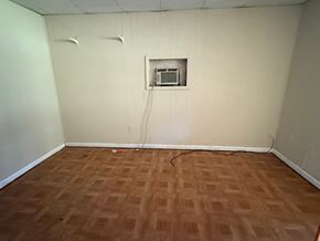 Palatka house for rent - A room with a brown floor and a white wall with a vent.