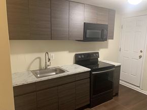 Baltimore house for rent - A kitchen with a sink, stove, and microwave.
