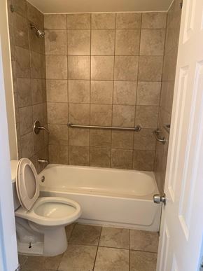 Baltimore house for rent - A white toilet is in a tiled bathroom with a white bathtub.