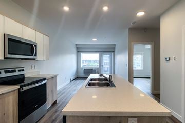 Saskatoon apartment for rent - A kitchen with a stove top oven and microwave above a counter.