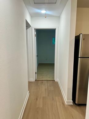 Houston apartment for rent - A hallway with a refrigerator on the right side.