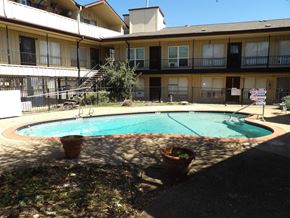 Dallas apartment for rent - A pool in a courtyard surrounded by potted plants and apartment buildings.