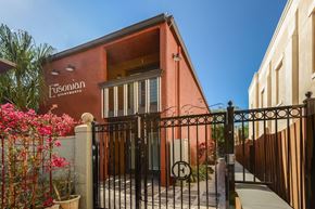 Tampa apartment for rent - The image shows a red building with a black gate and a sign that reads "Fusionian Apartments".