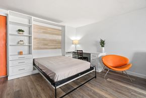 Honolulu apartment for rent - A bedroom with a bed, chair, and shelves.