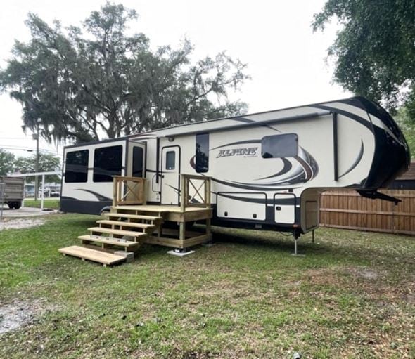 Lakeland apartment for rent - A white and black RV is parked in a grassy area.
