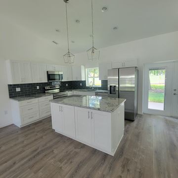Lakeland apartment for rent - A kitchen with white cabinets and a black backsplash.