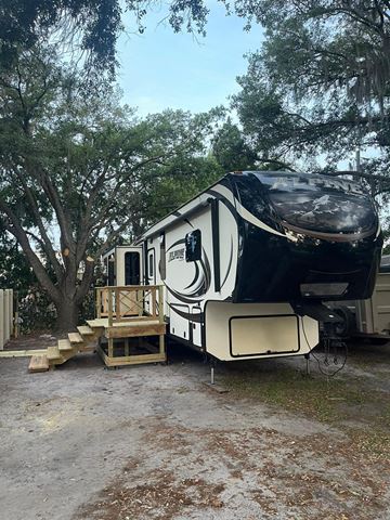 Lakeland apartment for rent - A black and white RV is parked in a wooded area.