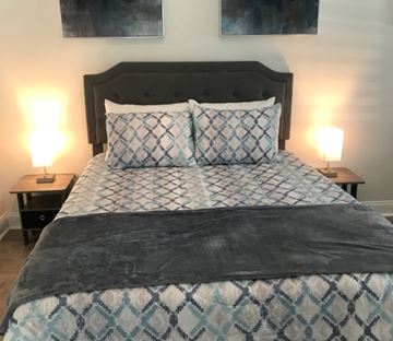 Lakeland apartment for rent - A bed with a black headboard and a blue and white patterned comforter.