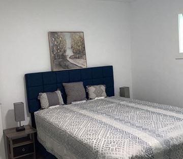 Lakeland apartment for rent - A bed with a blue headboard and a grey and white patterned duvet cover.