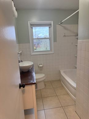 Johnson City house for rent - A white tiled bathroom with a toilet, sink, and bathtub.