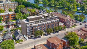 Ottawa apartment for rent - A large building sits in the middle of a street with a river in the background.