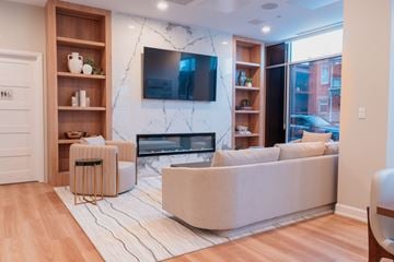 Ottawa apartment for rent - A living room with a white couch and a television mounted on the wall.