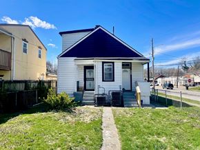 Louisville apartment for rent - A small white house with a blue roof is surrounded by a grassy area and a sidewalk.