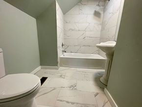 Louisville apartment for rent - A white toilet is in a bathroom with marble tile flooring.