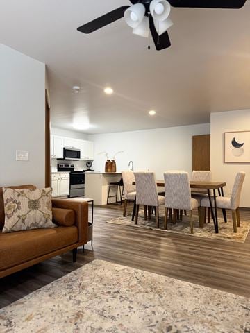 Hawarden apartment for rent - A modern living room with a brown sofa and a dining table set up.