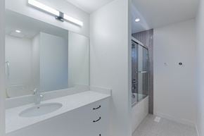 Edmonton apartment for rent - A white bathroom with a sink, mirror, and shower.