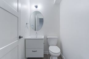 Edmonton apartment for rent - A white bathroom with a toilet, sink, and mirror.