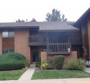 Boulder apartment for rent - A brick building with a balcony and bushes in front.