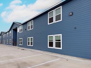 San Antonio apartment for rent - A blue building with white windows and a parking lot in front.