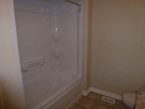 Kingston house for rent - A small white bathtub with a shower head and a drain in the corner.