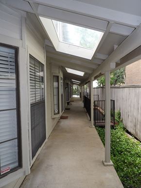 Dallas apartment for rent - A long, narrow walkway with a skylight above and a fence on the right.