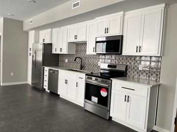 Tulsa apartment for rent - A kitchen with white cabinets and a black backsplash.