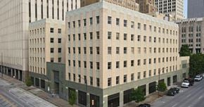 Tulsa apartment for rent - A large beige building with a green trim is situated on a busy street.